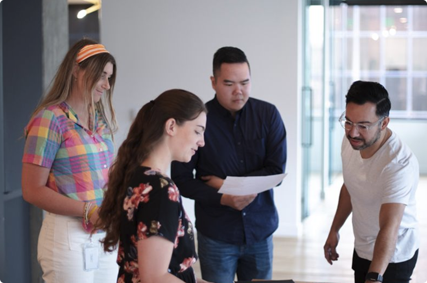 A group of Boncom co-workers reviewing a project around a table.