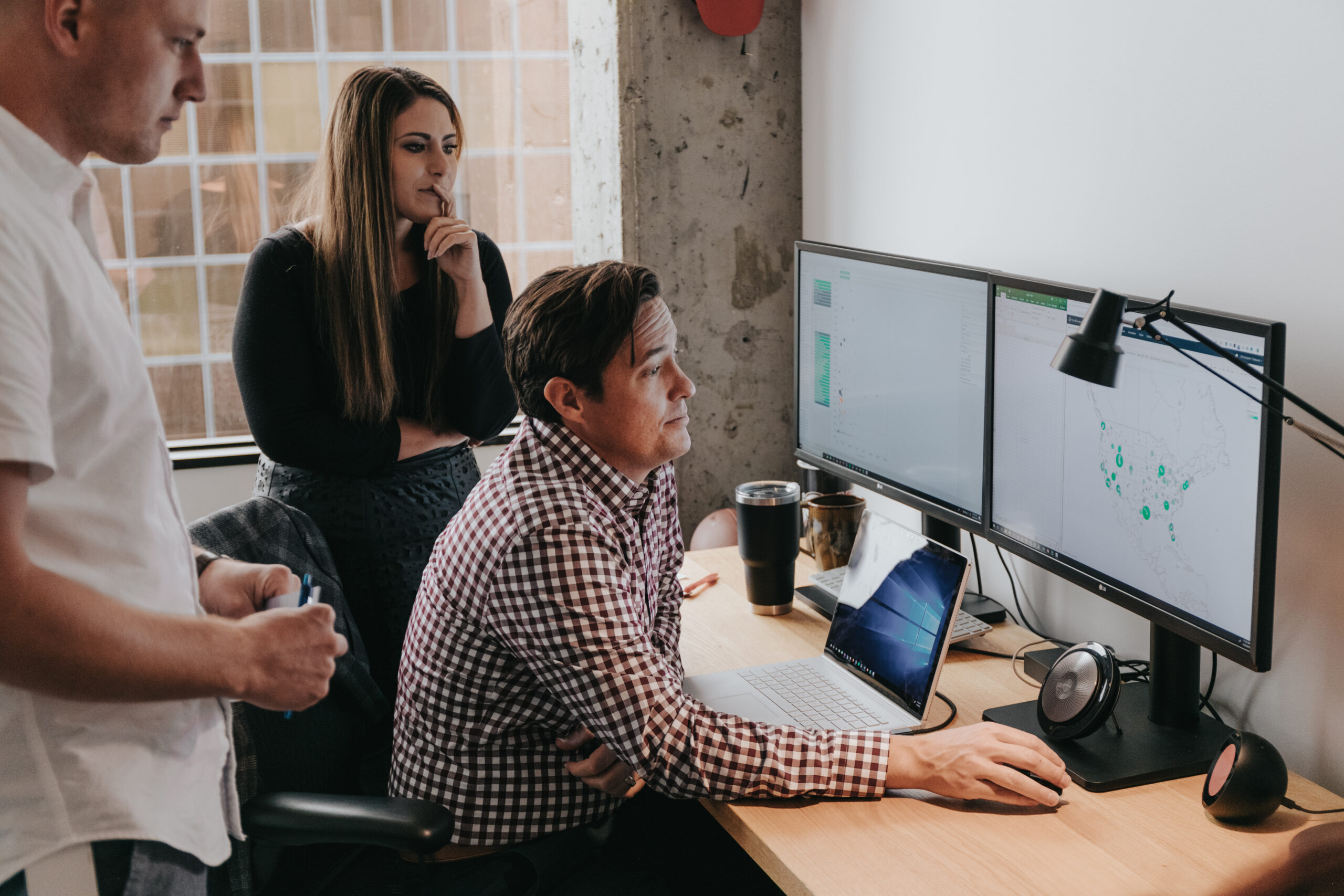 A team of co-workers reviewing information on a computer monitor.