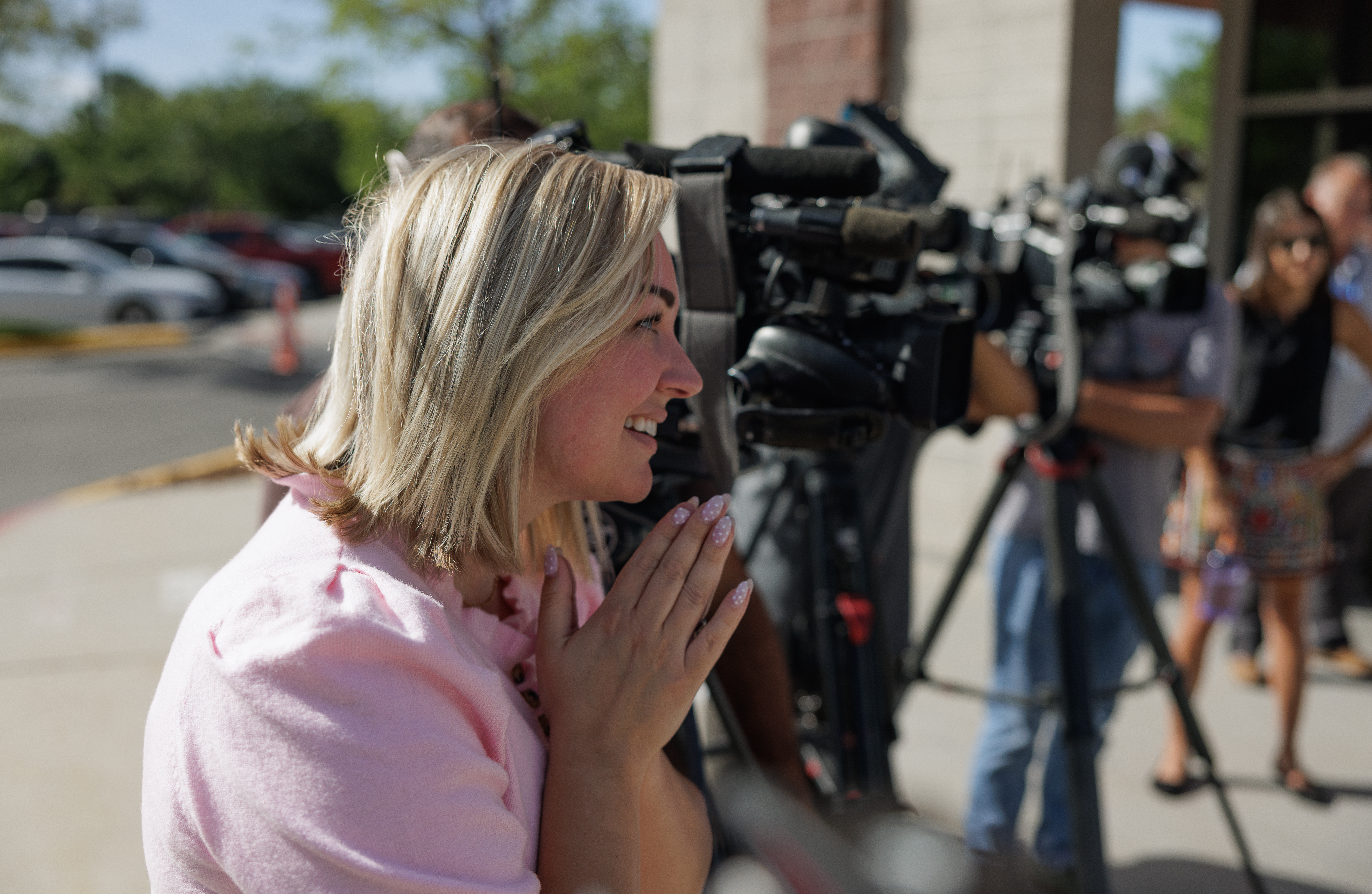 A woman standing near film camera crews.