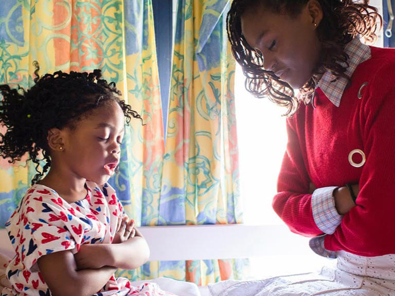 Two siblings facing each other and praying together.