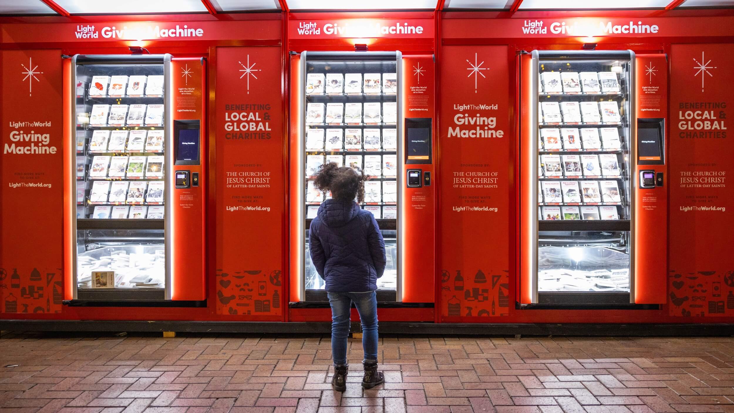 A young girl standing in front of a row of Giving Machines.