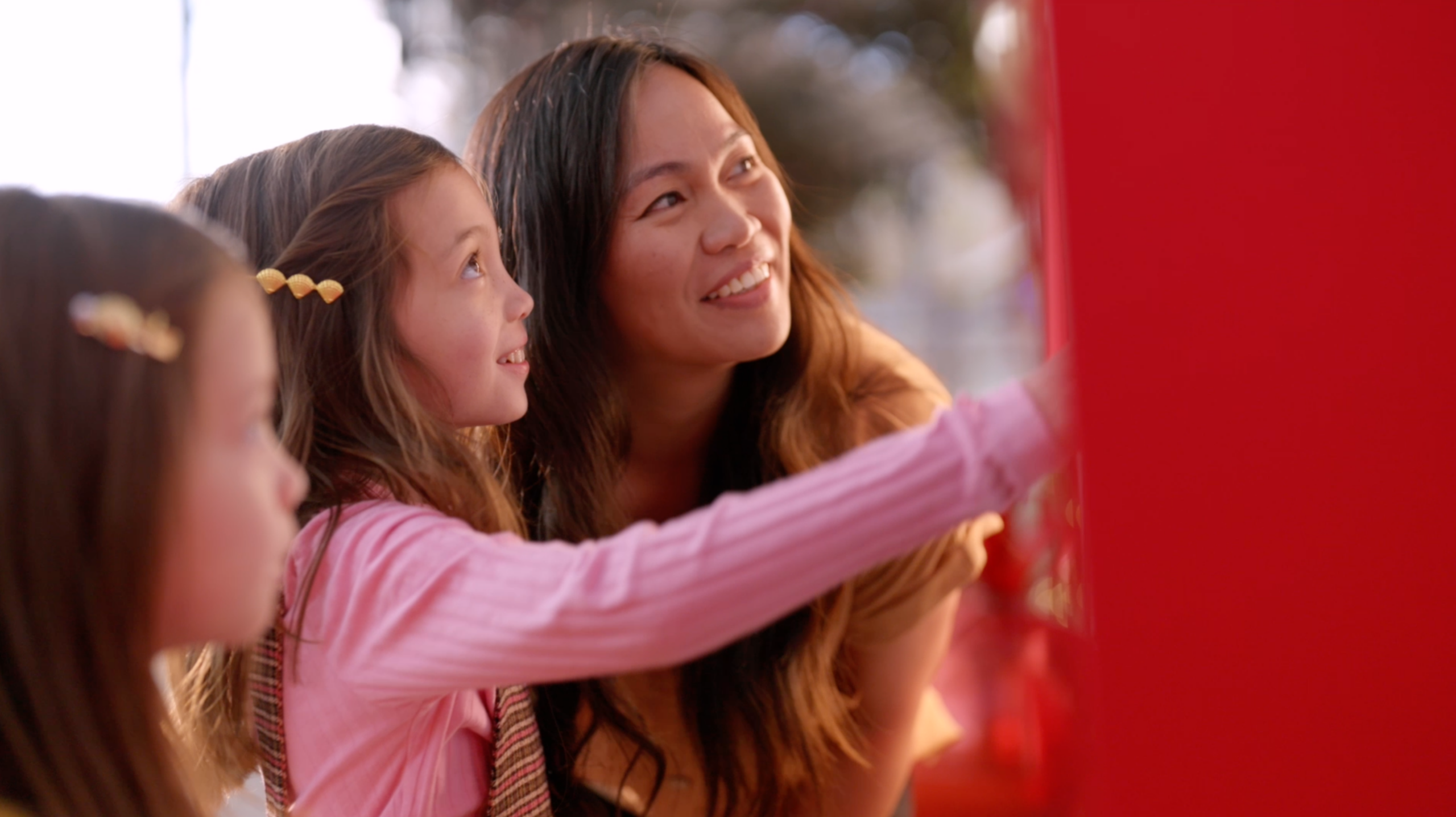 A mother and two daughters looking up at the Giving Machine options.