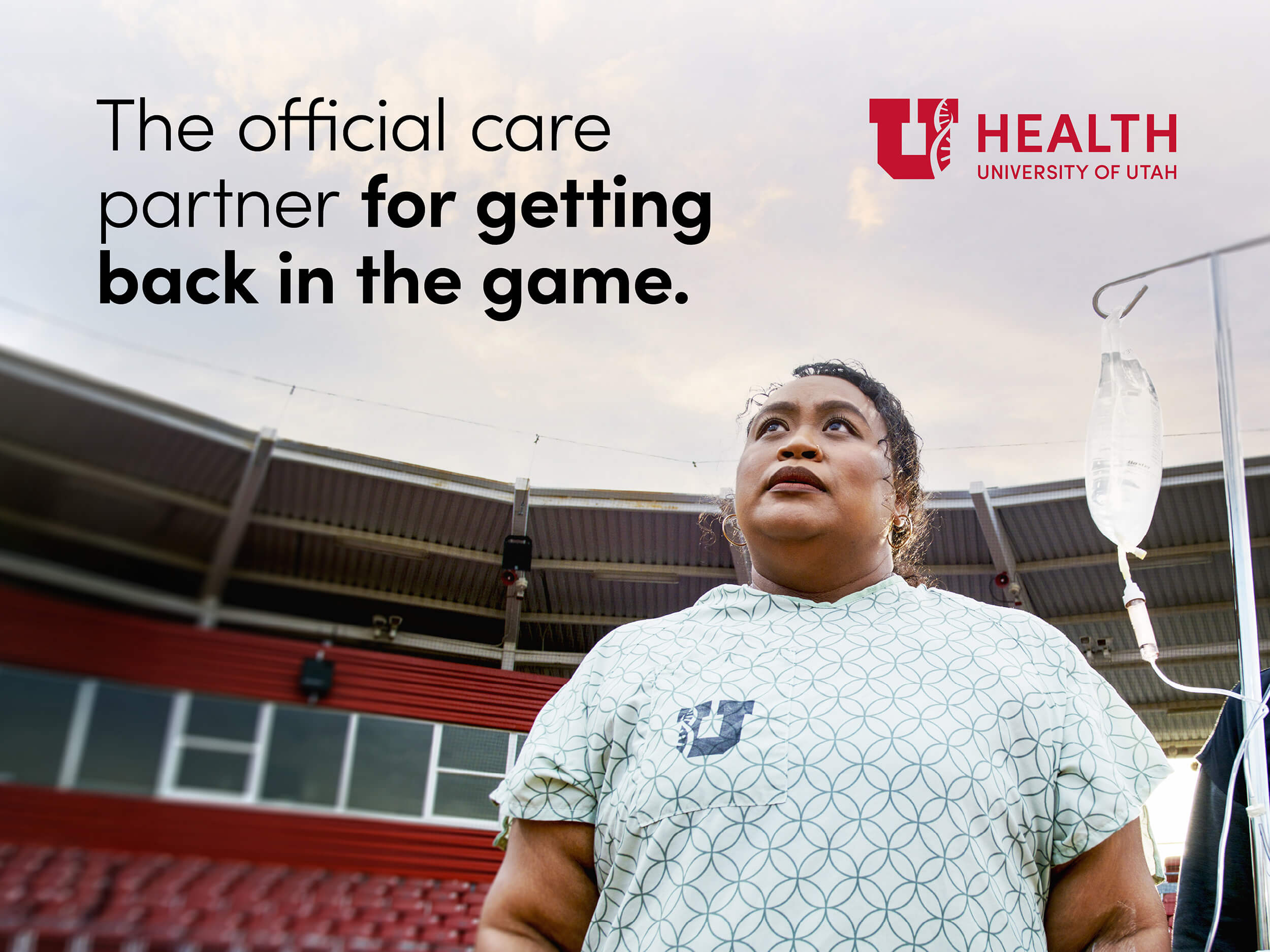 A woman in a hospital gown with an IV stand on a football field. The text says: The official care partner for getting back in the game.