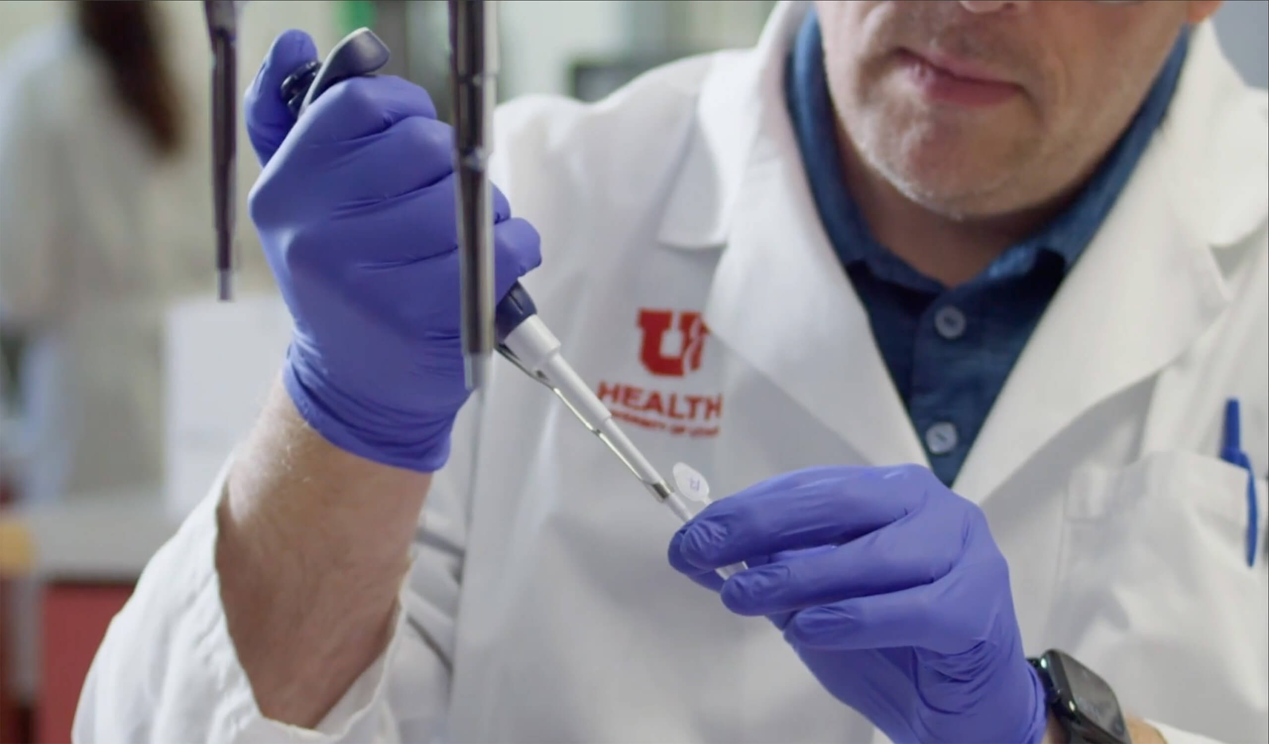 A lab technician adding liquid to a tube using a pipette.